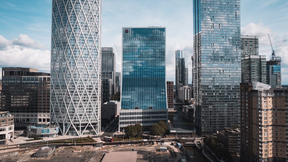 A high-rise urban landscape featuring multiple modern skyscrapers in a city center. The building on the left has a distinctive white lattice exterior pattern, while the central building has a reflecti