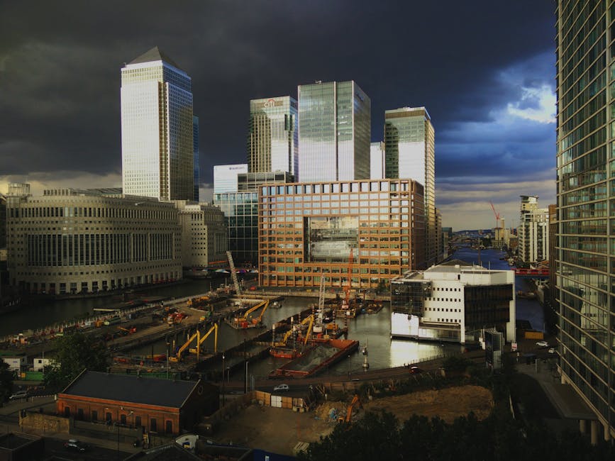 A high-rise urban landscape featuring multiple modern skyscrapers in a city center. The building on the left has a distinctive white lattice exterior pattern, while the central building has a reflecti
